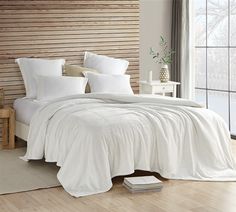 a bed with white sheets and pillows in a room