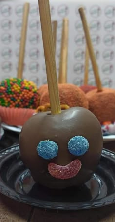 a chocolate apple that has been decorated to look like a smiley face with two sticks sticking out of it