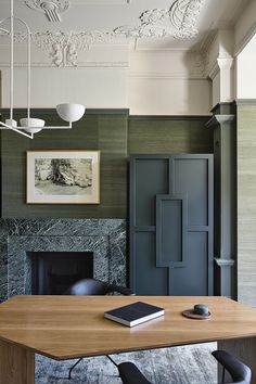 a wooden table sitting in front of a fire place next to a painting on the wall