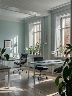 an office with two desks and chairs in front of large windows on either side of the room