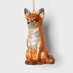 an ornament shaped like a fox sits on a white surface with a gold chain hanging from it's neck