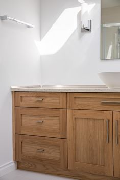 a bathroom with a sink, mirror and wooden cabinetry in the middle of it