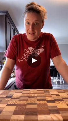 a woman standing in front of a wooden cutting board