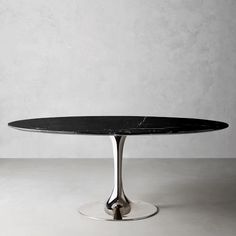 an oval black marble dining table with stainless steel base