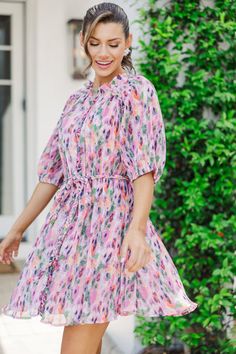 This dress is so cute! We love that print and all of that detailing! The ruffled, the pleating, the braided tie waist all come together to make an absolutely adorable dress!  Round neckline Button down front closure Short bubble sleeves Ruffled... Pink Flowy Dress With Tie Waist, Feminine Spring Tie Neck Dresses, Flowy Pink Dress With Tie Waist, Feminine Summer Dresses With Tie Neck, Pink Tie Waist Dress For Daywear, Patterned Spring Dresses With Ruffle Hem, Spring Patterned Dresses With Ruffle Hem, Patterned Dress With Ruffle Hem For Spring, Pink Tie-waist Dress For Spring