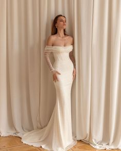 a woman standing in front of a curtain wearing a white dress