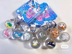 a bunch of key chains that are sitting on a white tablecloth with some cartoon characters in them