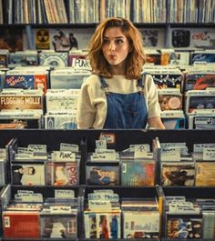 a woman standing in front of a store filled with cds