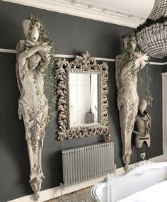 two statues are on the wall next to a mirror and radiator in a bathroom