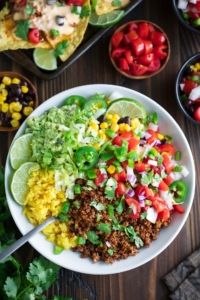 a white bowl filled with taco salad on top of a wooden table