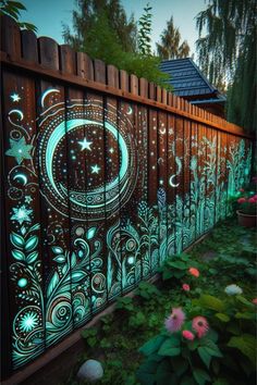 a fence that has been painted with glow in the dark paint and flowers on it