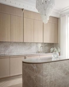 an elegant kitchen with marble counter tops and wooden cabinets, along with a chandelier