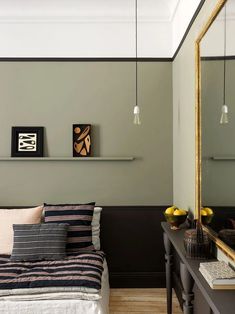 a bed sitting under a mirror next to a wall mounted shelf filled with vases