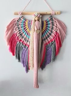 a wall hanging with tassels on it and a wooden stick in the middle