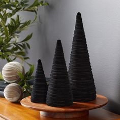 three black cones sitting on top of a wooden table next to a potted plant