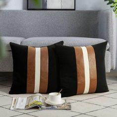 two black and brown pillows sitting on top of a white tiled floor next to a gray couch