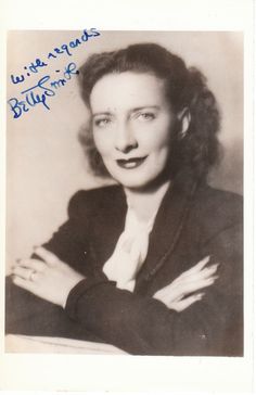 an old black and white photo of a woman with her hand on her chest, smiling