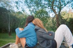 two people sitting on a bench with their backs to each other