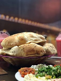 two pita breads sitting on top of a table next to a bowl of salad