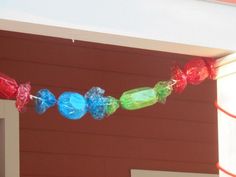 colorful candy candies are hanging from a line on the side of a red building