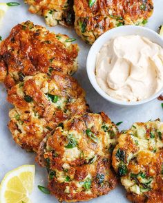 several crab cakes with lemon wedges and a small bowl of mayonnaise on the side