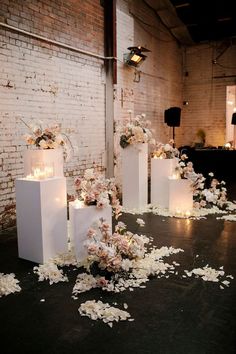 flowers and candles are scattered on the floor in front of white boxes with lit candles