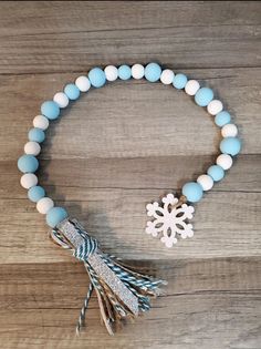 a bracelet with snowflake charms and tassels on top of a wooden table