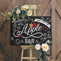 an apple bar sign with flowers and greenery