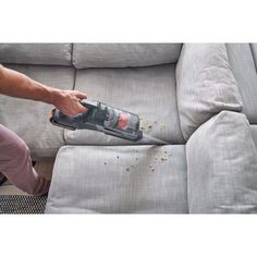 a person using a vacuum to clean a couch