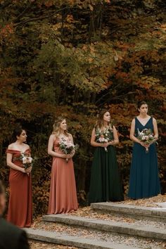 a group of women standing next to each other in front of some stairs and trees