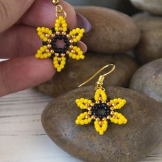 a pair of yellow and black beaded earrings sitting on top of a rock next to some rocks