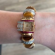 This Retro Omega Diamond & Ruby Watch Bracelet is a dazzling masterpiece in 18k rose gold. Geometric, romantic, and one of a kind. This vintage bracelet features a hooded watch that hides the dial, turning the watch into an ornate bracelet. Known as vintage "fancy case watches", this statement bracelet exudes beauty in every detail. A pave of diamonds decorate the case and bracelet. Two rows of red rubies add a deep crimson gemstone color, complementing the 18 karat rose gold composition. Shop m Art Deco Gold Jewelry With Diamond Hour Markers, Luxury Collectible Quartz Jewelry And Watches, Gold Art Deco Diamond Watch, Art Deco Gold Diamond Watch Gift, Elegant Gold Diamond Watch With Rotating Bezel, Gold Art Deco Diamond Watch Gift, Luxury Gold Jewelry And Watches Collectible, Luxury Gold Jewelry And Watches For Collectors, Luxury Gold Collectible Jewelry And Watches