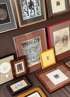 many framed pictures are on the wall with different colors and sizes, including one that is brown