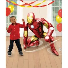 a little boy standing next to a giant iron man balloon