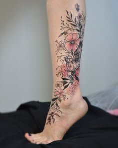 a woman's foot with flowers and leaves on the bottom part of her leg