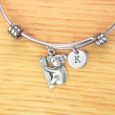 ♥ Koala Bear Charm Bangle Koala Bracelet Koala Charm Bracelet Koala Gift Animal Charm Personalized Initial Bangle Australia Bear Gift ♥ This is a silver-tone Koala Bear charm with hand stamped initial charm on an expandable bangle. ♥ You will receive 1 bangle ♥ Koala Charm 19.3x14,5x2 mm. ♥ Initial charm stainless steel 10mm choose from a drop-down menu. ♥ Bangle 57-64 mm ♥ additional initial https://www.etsy.com/listing/766732811 ♥ We strive for next day shipping, but we do not ship on Saturday Adjustable Novelty Charms Bracelets, Personalized Novelty Charm Bracelet, Animal Design Dangle Jewelry Gift, Novelty Bracelet Jewelry As Gift, Novelty Bracelet Jewelry Gift, Novelty Bracelet Jewelry For Gifts, Novelty Adjustable Charm Bracelet, Cute Adjustable Charm Bangle Bracelet, Adjustable Novelty Charm Bracelet With Lobster Clasp