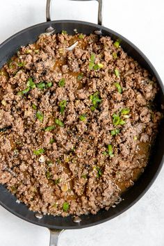 a skillet filled with ground beef and green onions