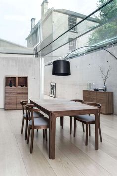 a wooden table and chairs in a room with glass walls, windows, and wood flooring