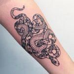 a tattoo on the arm of a woman with a snake and flower design in black ink