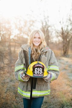 a woman in a fireman's jacket holding a helmet