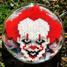 a red and white beaded clown face on a glass plate