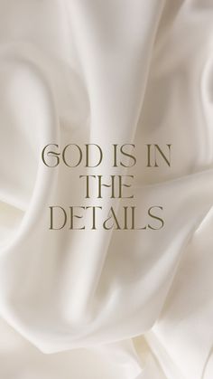 the words god is in the details written on white fabric with gold foiled lettering