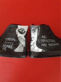 two black shoes with drawings on them sitting on a red surface next to each other