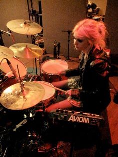 a woman sitting in front of a drum set