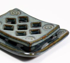 a decorative ceramic object sitting on top of a white tableclothed surface with circles and rectangles in the center