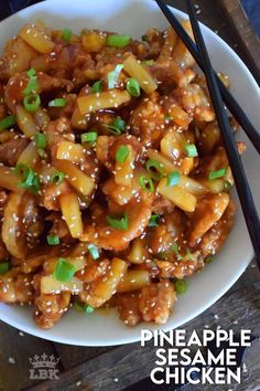 a white bowl filled with pineapple sesame chicken and chopsticks next to it