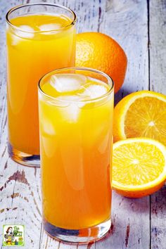 two glasses filled with orange juice next to an orange slice