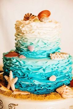 a three tiered cake decorated with seashells and starfish