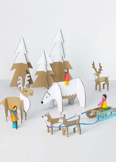 paper cut out animals and people on sleighs in front of snow - covered trees