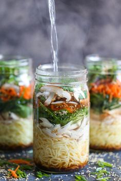 three mason jars filled with noodles and vegetables